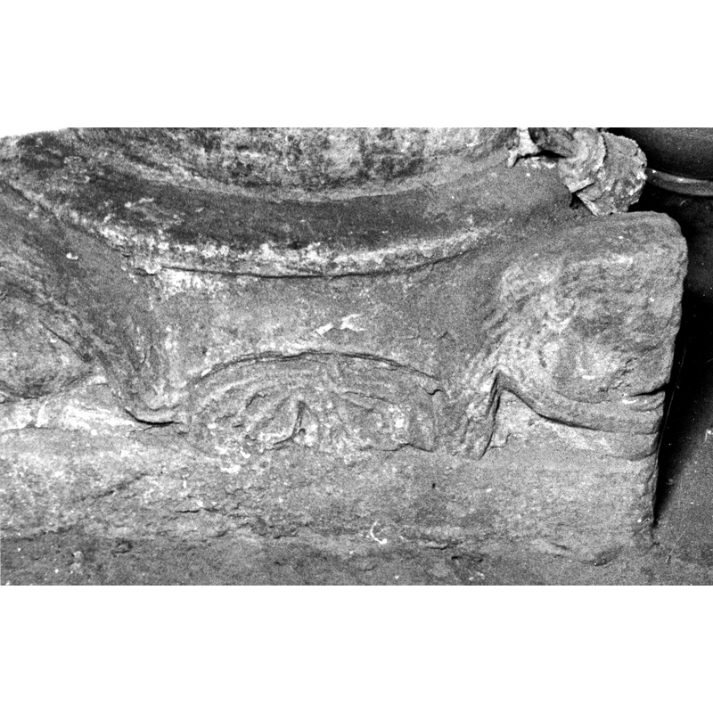 Source caption: 'Detalle de la basa de la pila bautismal; está decorada con mascarones y elementos geométricos [...] pila bautismal de la iglesia de San Martín de Arlucea" [NB: a stylised plant in the middle?]