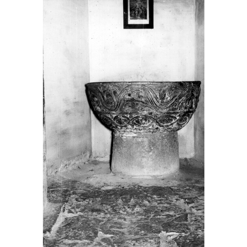 Source caption: "Pila bautismal de la iglesia de San Pedro de Treviño [...] Vista frontal de una pila medieval fechable en el siglo XIII. La copa está muy decorada y presenta guirnalda ondulada, con hojas curvadas y espigas entre ellas; la parte inferior presenta entrelazado con escamas en su interior"