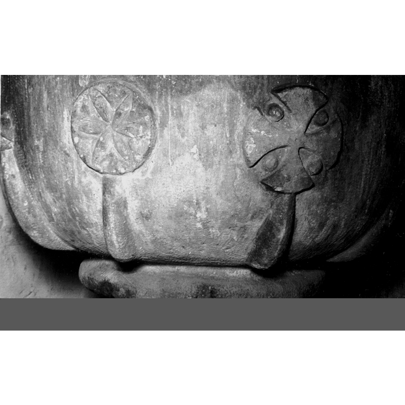 Source caption: "pila bautismal de la iglesia de Santa Eulalia de Chinchetru [...] Detalle de los distintos motivos decorativos de la taza; presenta gallones que saliendo de la base se ensanchan en los remates y se ornamentan con diversos motivos. Se muestra una roseta geométrica inserta en un círculo y una cruz de brazos, curvos, anchos, con bolas entre ellos"