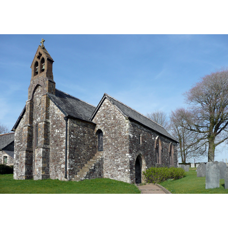 Source caption: "The church of St Michael and All Saints, Bulkworthy. This has an unusual design; the porch is built into the south aisle, and over it is the priest's chamber accessed via an outside staircase. The bellcote with two bells is supported by twin buttresses, almost hiding the narrow west window. The church was built by Sir William Handford, Chief Justice of the King's Bench, between 1414 and 1442."