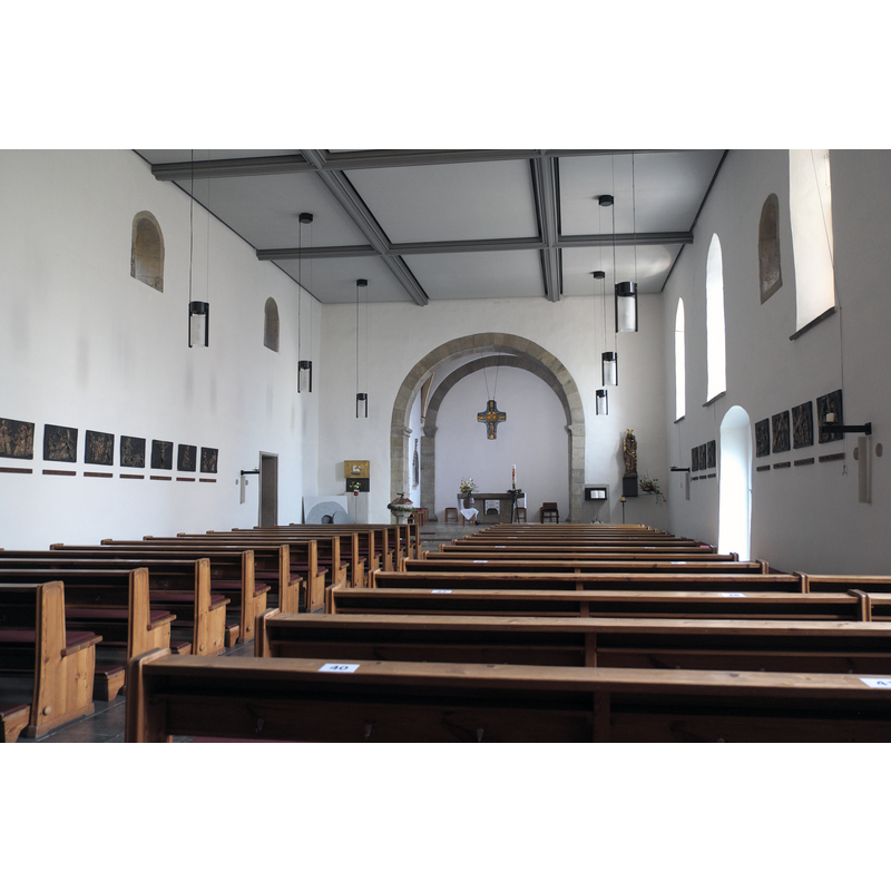 Source caption: "Katholische Pfarrkirche St. Johannes Baptist in Jena (Thüringen/Deutschland), Innenraum" -- showing the font and cover in the northeast corner of the nave, just west of the chancel arch north pillar