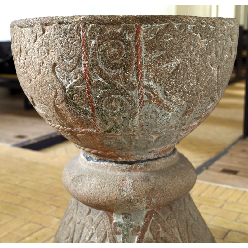 an almost identical decoration as the corresponding one on the west side, but here the lions are reversed: the frontal head on the left [gardant] and the profile head on the right -- the red paint may be remains from the time when the font was totally painted and gilded