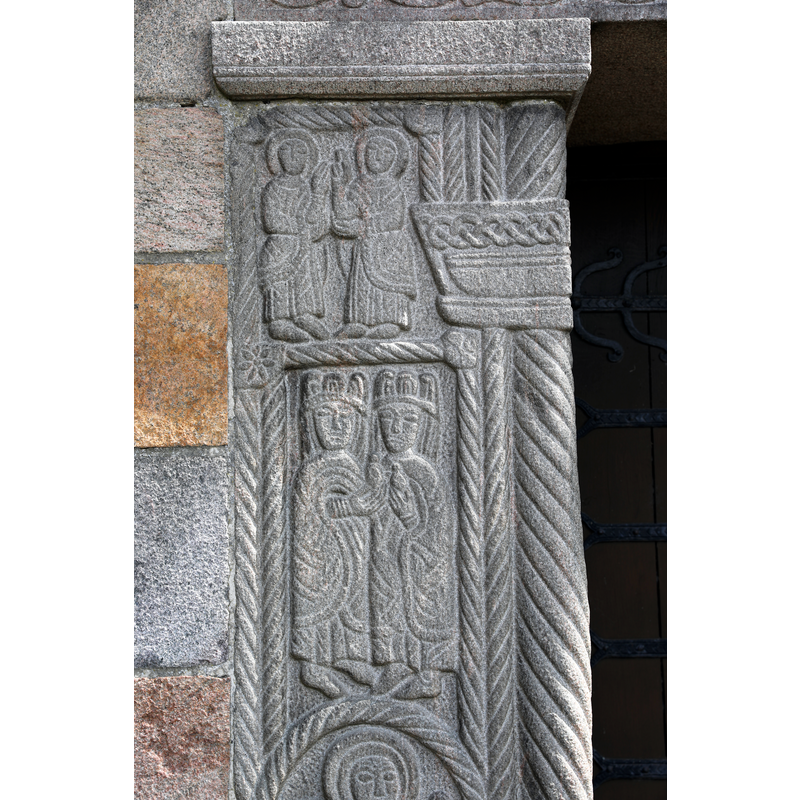 in a blessing pose, wearing very ornate or priestly robes -- formerly the south portal of the medieval church
