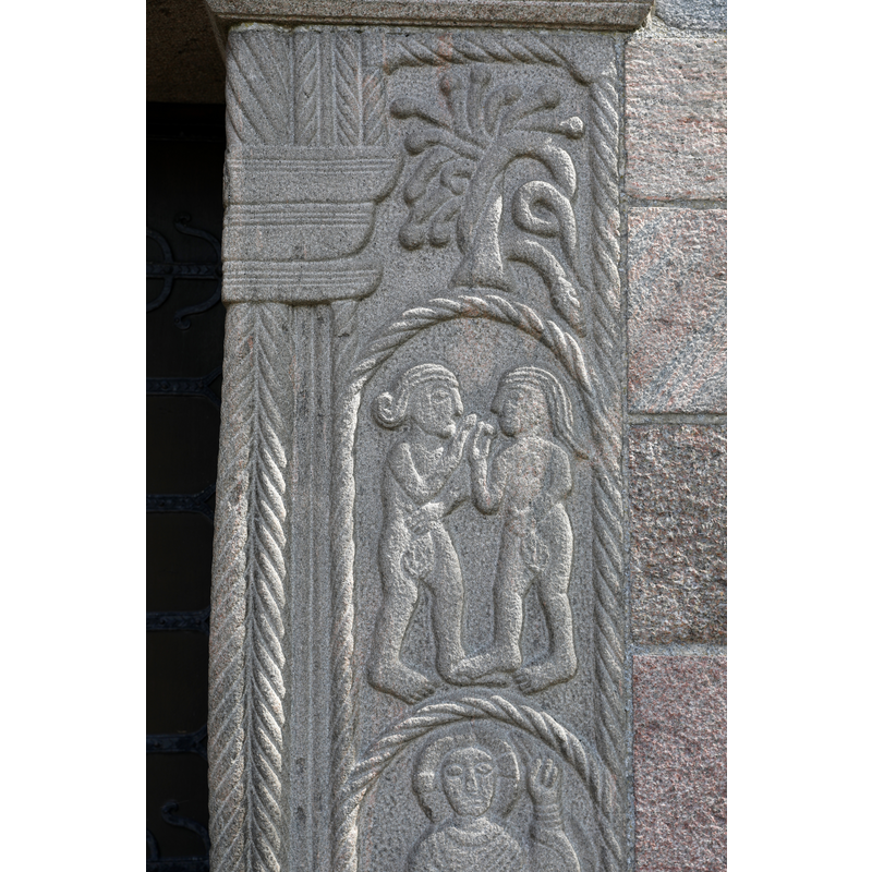 Adam and Eve facing each other, holding the fruit in their hands and holding leaves over their pudenda -- formerly the south portal of the medieval church