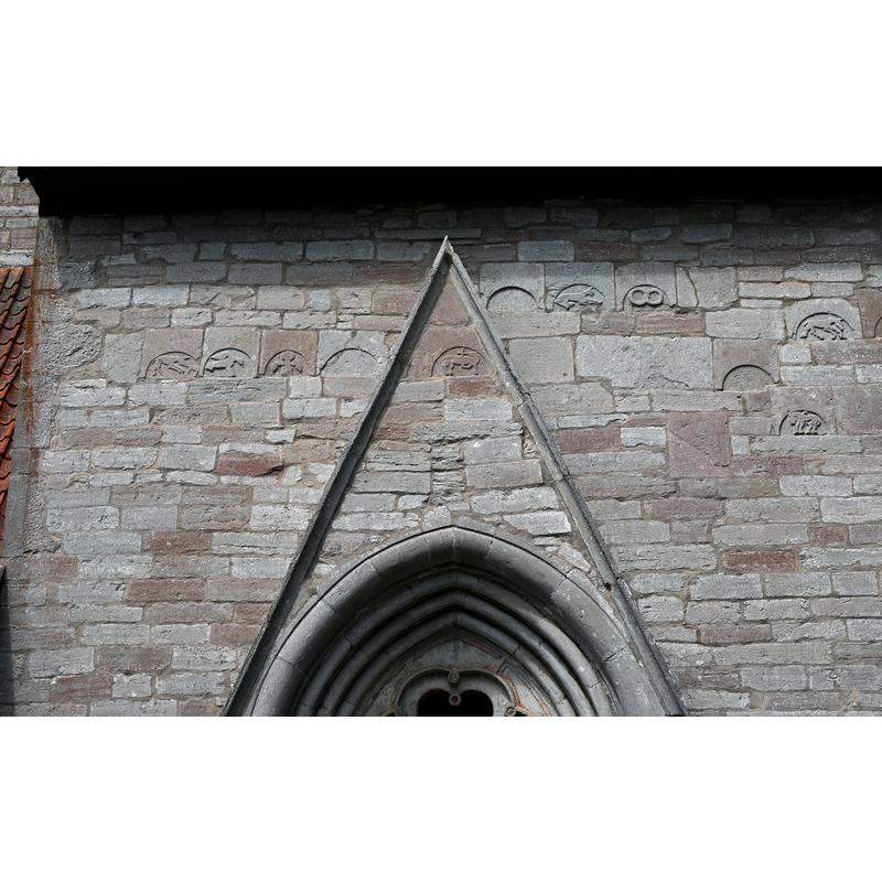 the carved motifs above the portal include animals, a human, symbols and an Agnus Dei