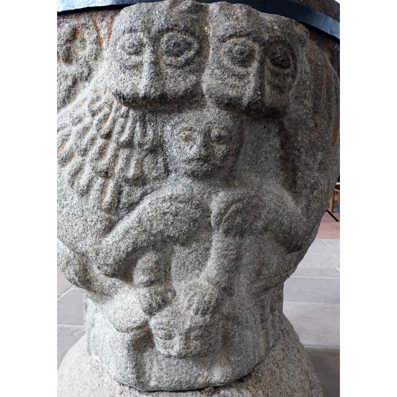 on the narrow east side of the font, with the bodies of the lions occupying most of the long north and south sides of the font; the lions have a paw each on the shoulders of the man, himself standing or sitting on a head (?) -- it is not a hunting scene, nor does it seem to be Daniel in the lions' den