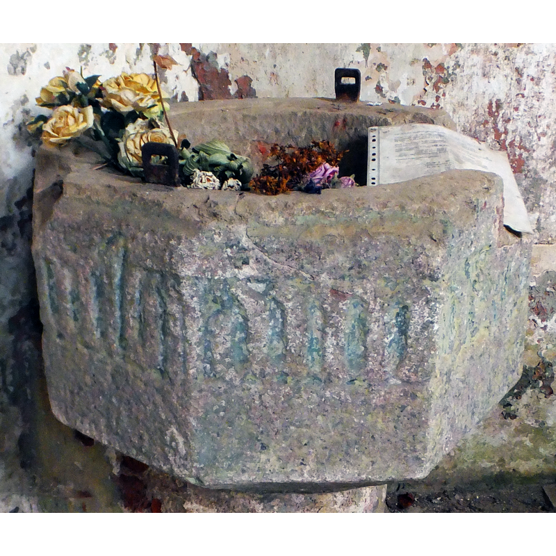 showing two metal staples from an old cover; the decoration on the basin is too eroded to be identified but it looks like an inscription in Gothic lettering; the background retains the old coloured backgound