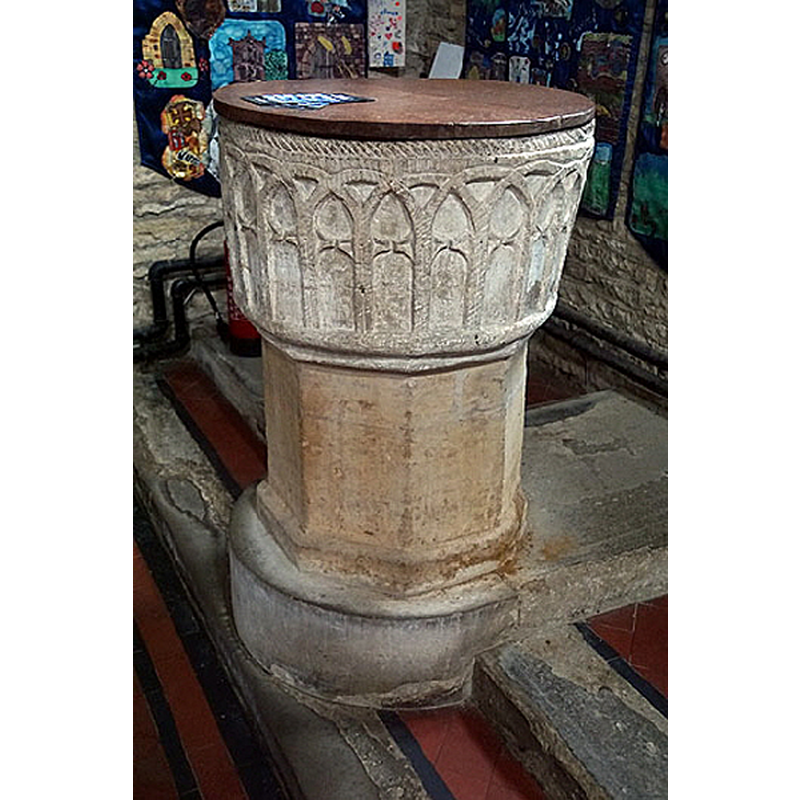 Source caption: "The font. With its commonplace blind arcading decoration and its cable moulding around its rim, it is a classic Norman design. The Church Guide, however, points to the cusping within each arch and suggest that it is likely, therefore, to be an early thirteenth century font with a late Norman flavour."