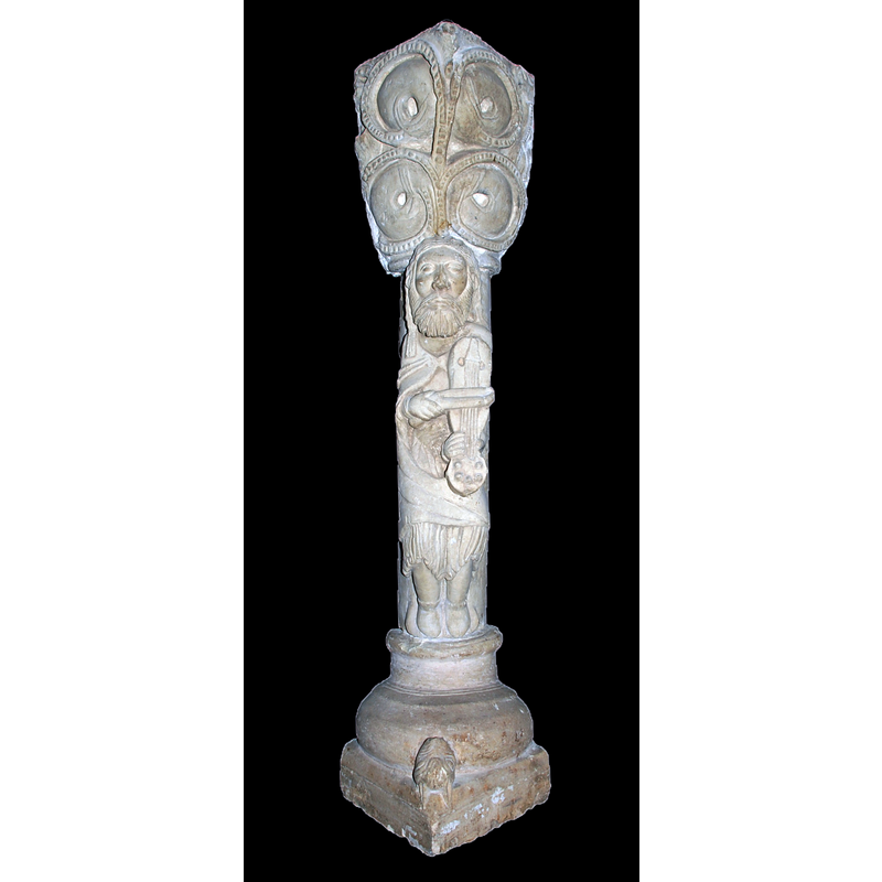 Source caption: "Estatua-columna en la iglesia de San Andrés de Revilla de Collazos (Palencia, Castilla y León). Actualemente hace función de atril y es la pieza escultórica más conocida del edificio. Alta de 1,20 m, se compone de basa sobre plinto de prominente toro inferior con una cabecita de felino a modo de garra, escocia lisa y toro superior atrofiado. Adosada al fuste aparece la figura de un tañedor de viola con arco, vestido con túnica cuyos fruncidos y ondulados pliegues aparecen bajo su sayón. Su rostro hierático luce larga cabellera, barba mediana y ojos almendrados e inexpresivos. Bien que sean evidentes las desproporciones del canon, éstas no restan gracia a la figura, que se despega airosa del fuste que la sustenta. El gran capitel que remata la columna se decora con dos series de tallos perlados vueltos y rematados por hojas que acogen cuatro gruesas bolas que pudieran querer representar frutos. Se ha supuesto esta columna perteneciente a la desaparecida ventana central del ábside. Sus dimensiones y el bisel de la parte posterior así lo sugieren, aunque la tipología de la basa y astrágalo no concuerda con los de las columnas conservadas en la ventana sur del hemiciclo. Se viene asimilando a este músico con el rey David, aunque falten elementos definitorios para determinar con certeza tal identificación."