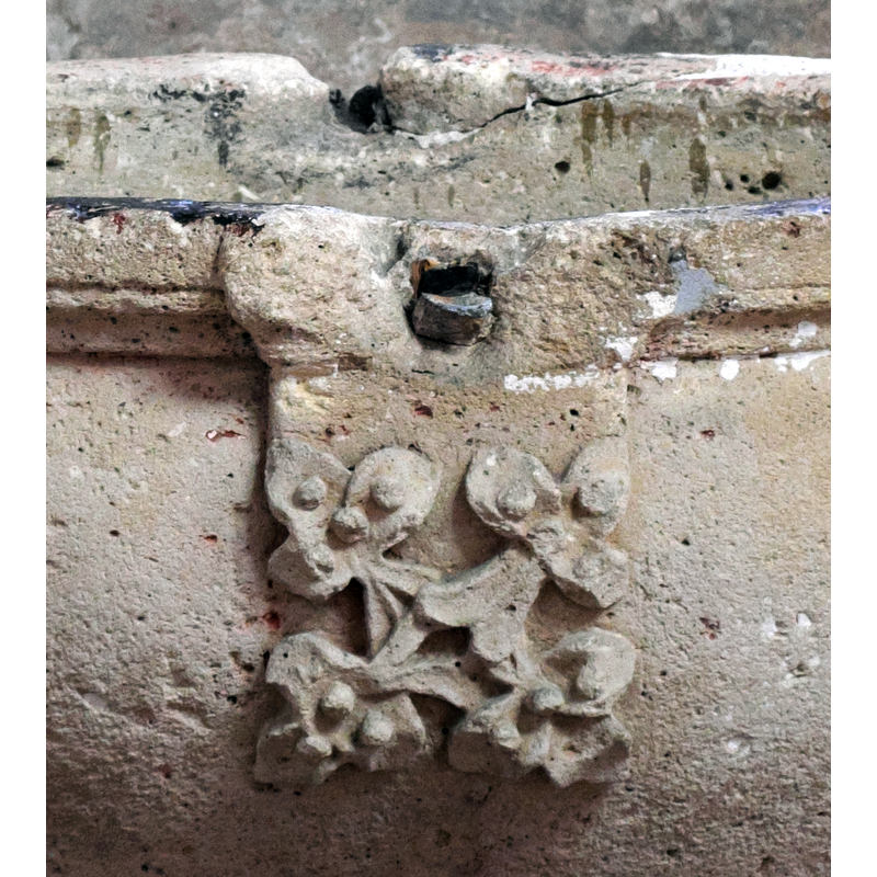 showing the upper rim moulding, the foliated motif (a similar one at the back), the metal staples of the font cover anchorings and some of the damage caused to the stone by them
