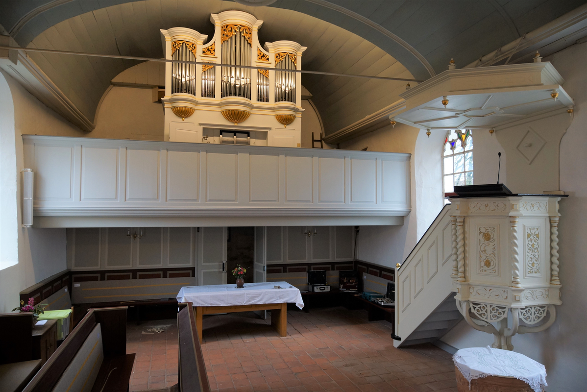 the baptismal font, covered with a cloth, is partially visible in the bottom-right corner of the image