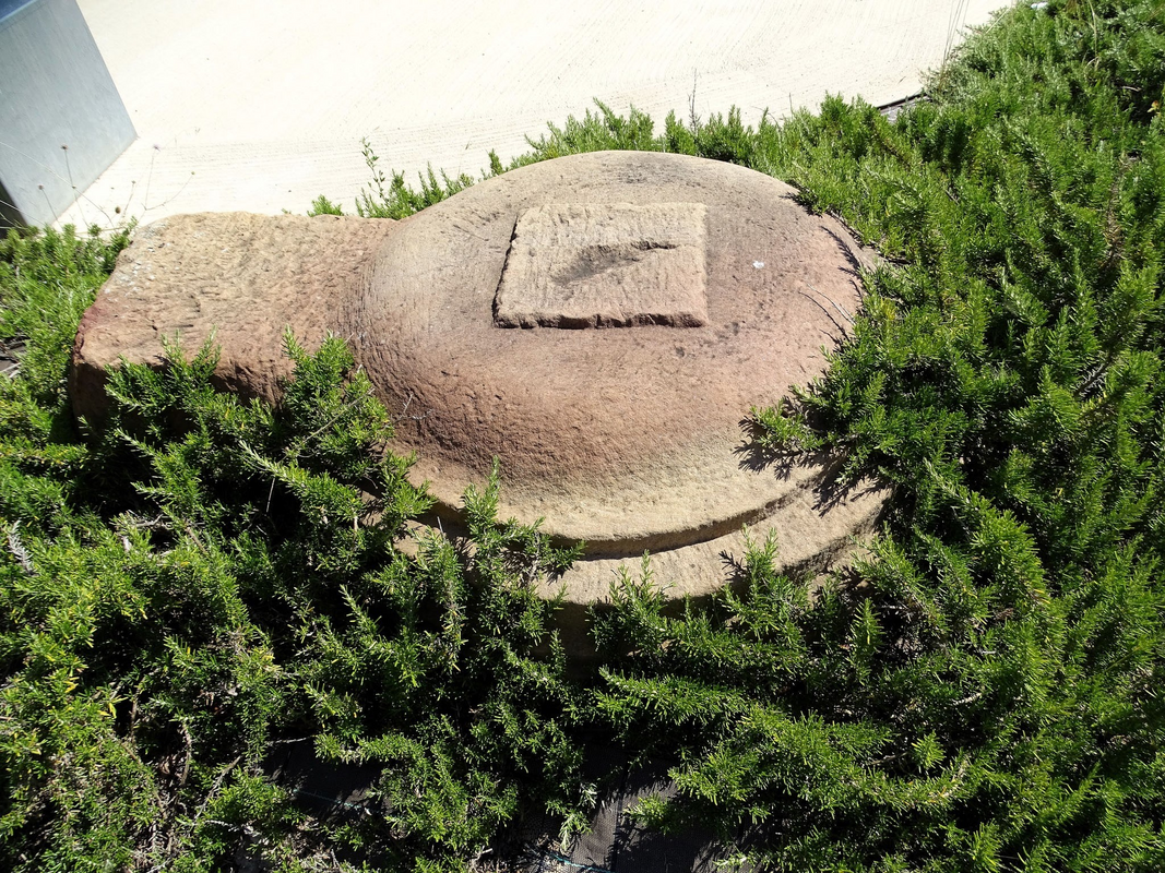 appears to be the base of the old font; now relegated to the outside of the new church