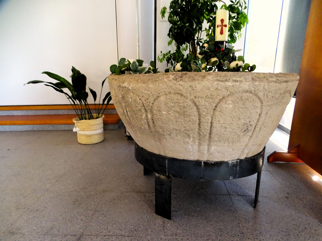 the old basin now mounted on a modern metal base and installed in the new church