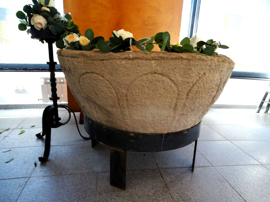 the old basin now mounted on a modern metal base and installed in the new church