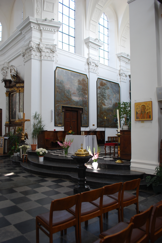 "Vue de l'intérieur de l'ancienne collégiale Saint-Georges et Sainte-Ode à Amay." -- showing the modern font and cover at the foot of the chancel steps