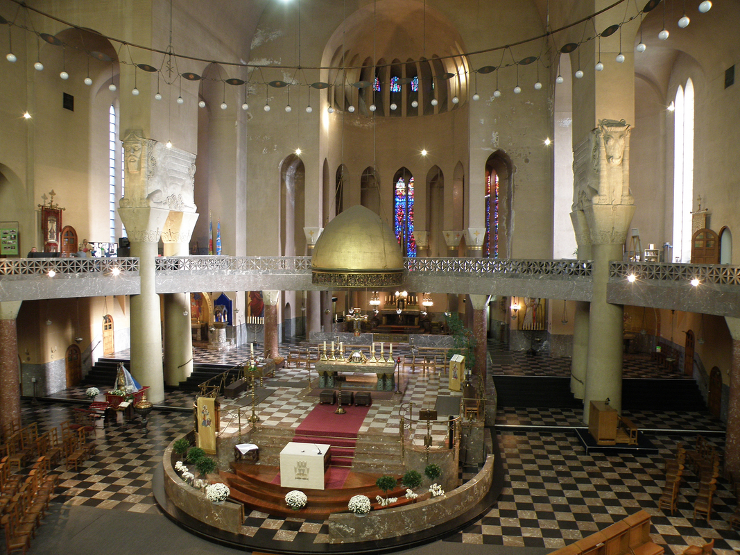 "Anvers, Belgique. Église Saint-Laurent, sise à l’angle des rues Van Schoonbekestraat / Markgravelei, de style Art déco et néo-byzantin. Architecte : Jef Huygh, date d’achèvement 1934 (clocher : 1941) / Antwerpen, hoek Markgravelei / Van Schoonbekestraat. Sint-Laurentiuskerk, in Art Deco en neo-Byzantijnse stijl. Ontwerp van Jef Huygh, inwijding 1934 (toren 1941)" -- showing the present, 19thC baptismal font and cover on the left, outside the chancel area.