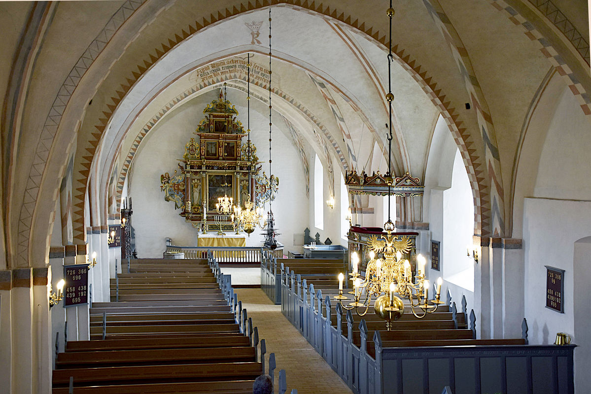 "Interior of Nordby Kirke - nave" -- the top of the font is visible at the far [east] end, left [north] side