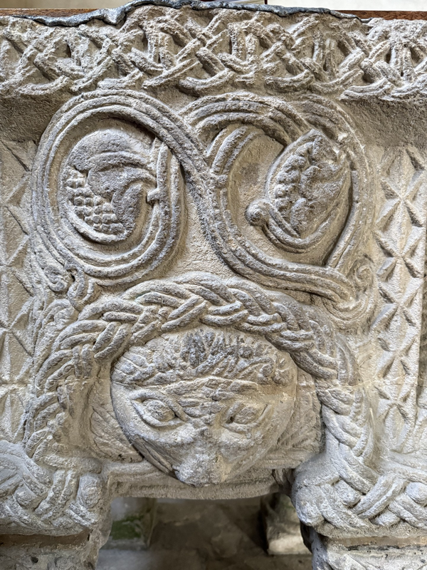 interlace below the upper rim; 3-strand vine with leaves and fruit; dogtooth vertical bands on the sides; 2-strand braid frames the animal head below