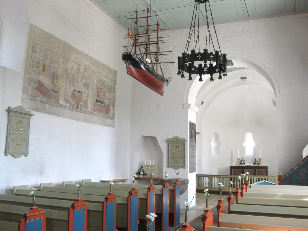 " Det indre af Sankt Povls Kirke (Sct. Povls Kirke) på Bornholm." -- the font is partially visible in the northeast corner of the nave, by the north pillar of the chancel arch