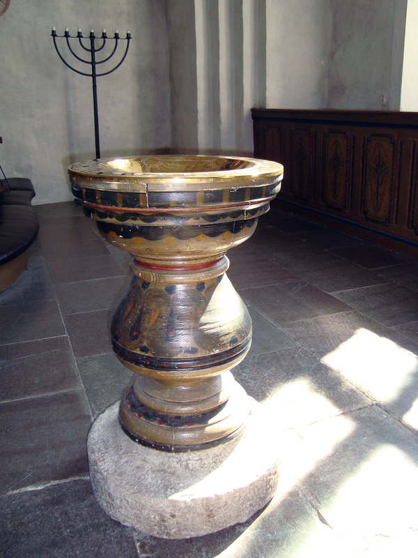 "Torsångs kyrka interiör" -- the composite font: a wooden basin and pedestal base of 1715, raised on a 13th-century lower base of Gotland limestone