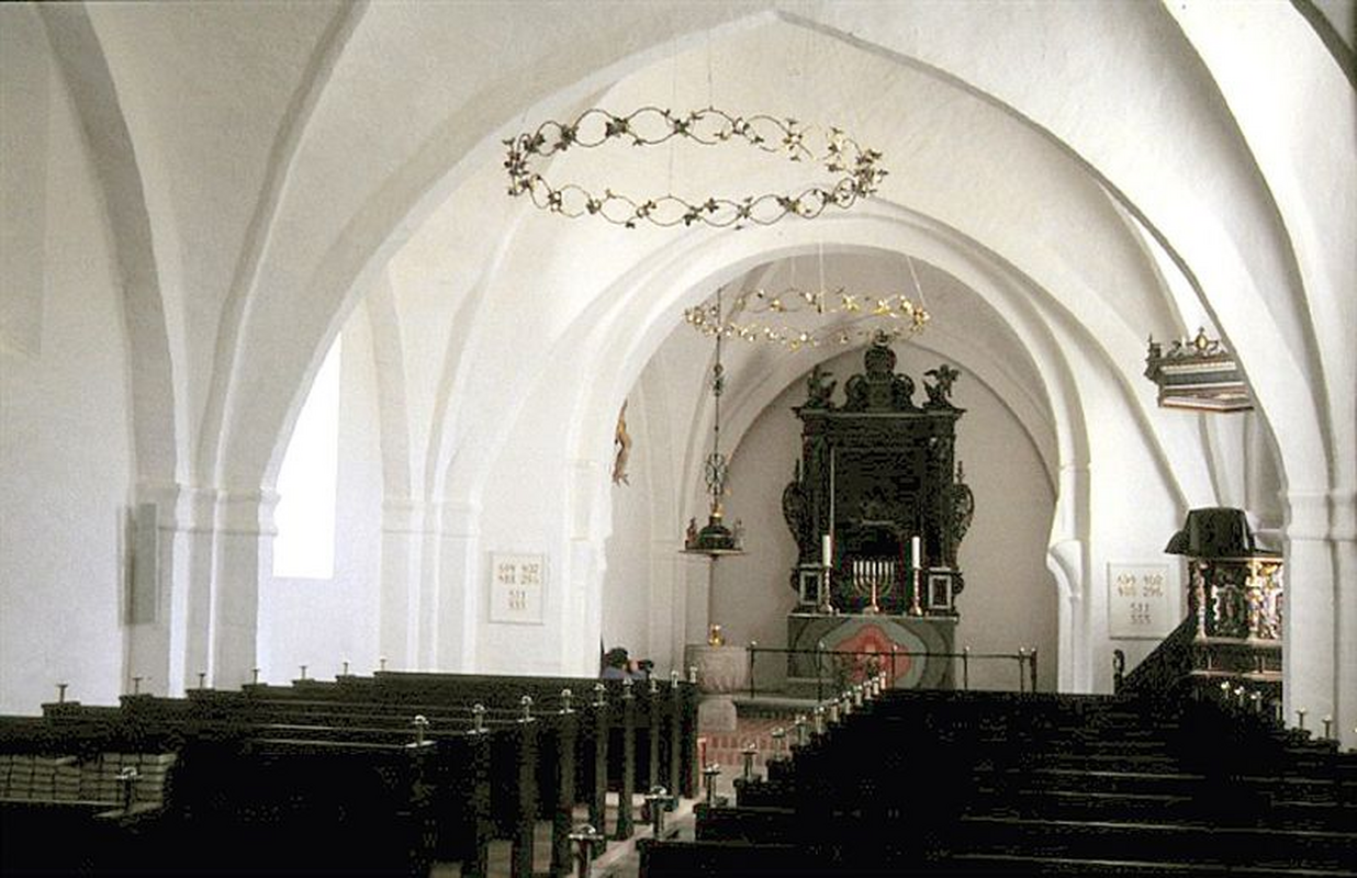 "Tikøb Kirke i Danmark. Skibet set mod øst" -- showing the font partially in the northeast corner of the nave