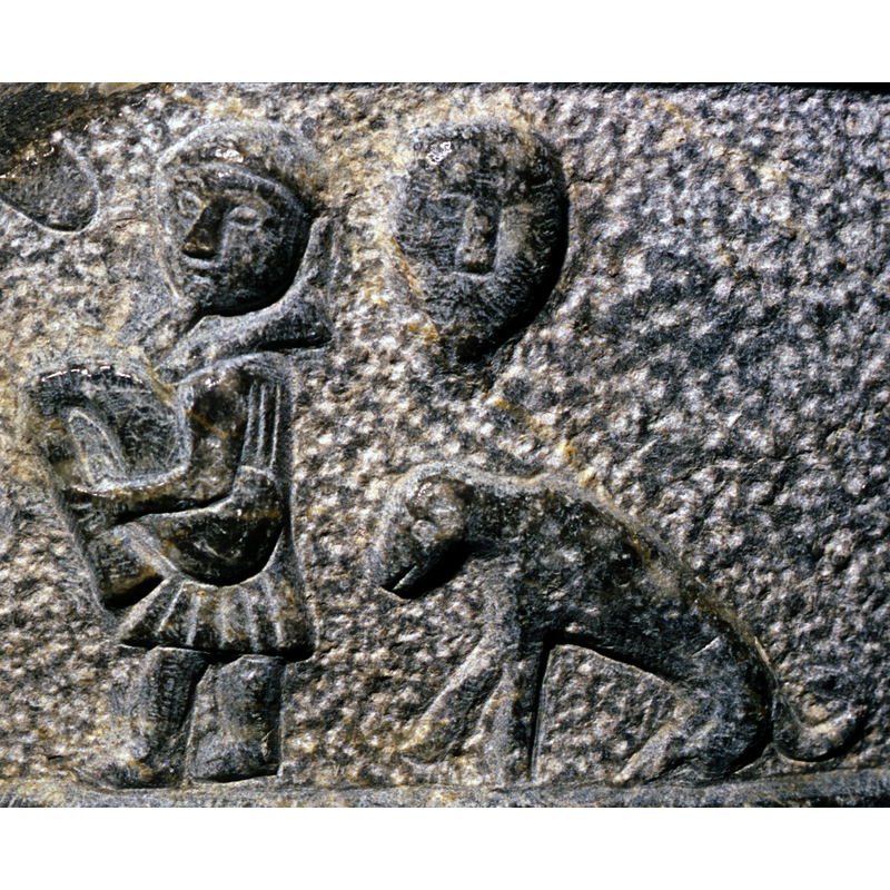 a large face resembling a carnival mask appears to float above the dog; they both appear to be part of the dancing scene