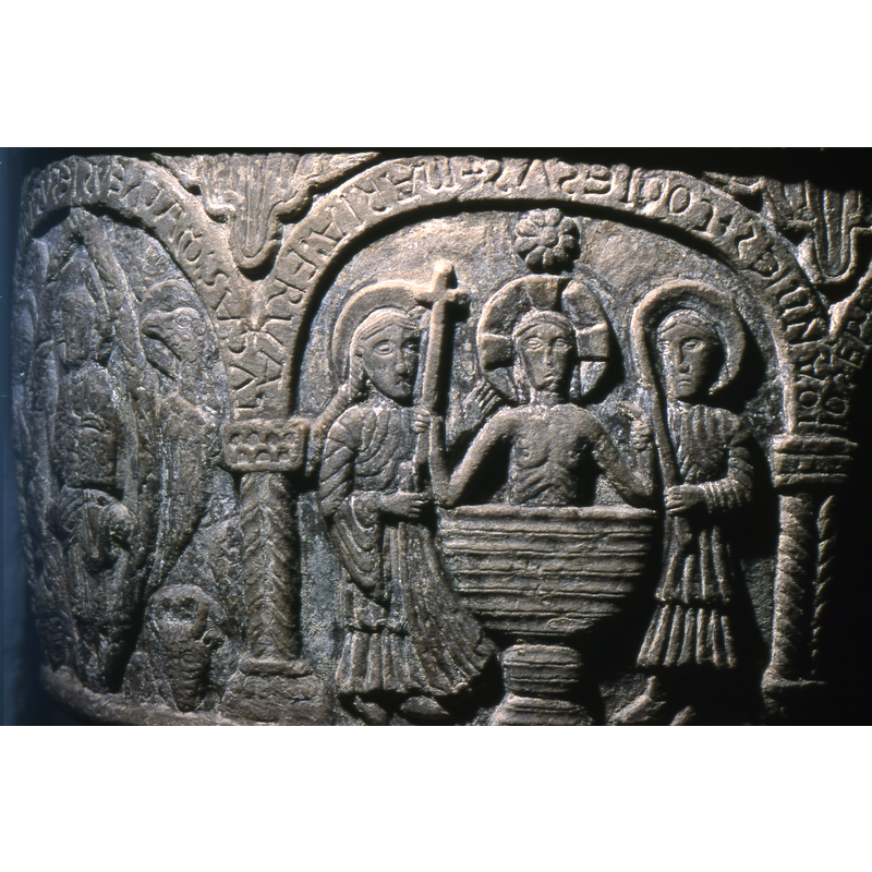 Christ kneels in a baptismal font, holding a large cross. The Virgin Mary stands on the left holding a cloth. St. John the Baptist stand on the right. John the Baptist holds a paschal candle in his left hand and holds up Christ's left arm with his right hand. A  star shines above Christ. This is a representation of Christ as an adult.