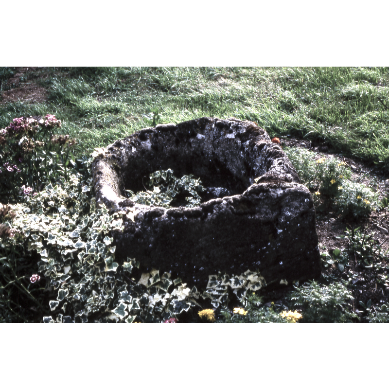 half-buried in the churchyard; it appears to be a font basin