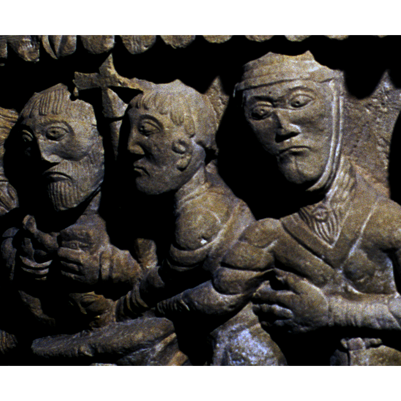 the baptism scene; the priest, at the left, holds in his right hand the infant partly into the water of the font; in his right hand is a container; the figure in the centre  holds a processional cross in his right hand, the left hand touches the infant inside the font; the right figure's arm is also stretched towards (inside?) the font; notice her elegant dress and the broach at her neck