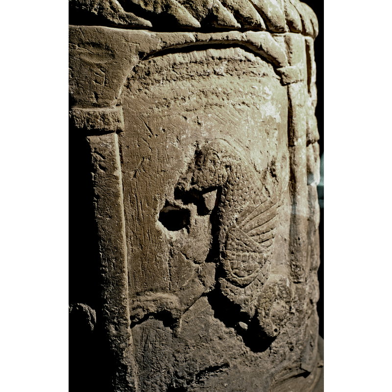 Winged Dragon looking toward the left. A hole is dug into the side next to the dragon. This is not related to a previous lid, but more likely a drain made when the font was used as garden ornament (?) or the like