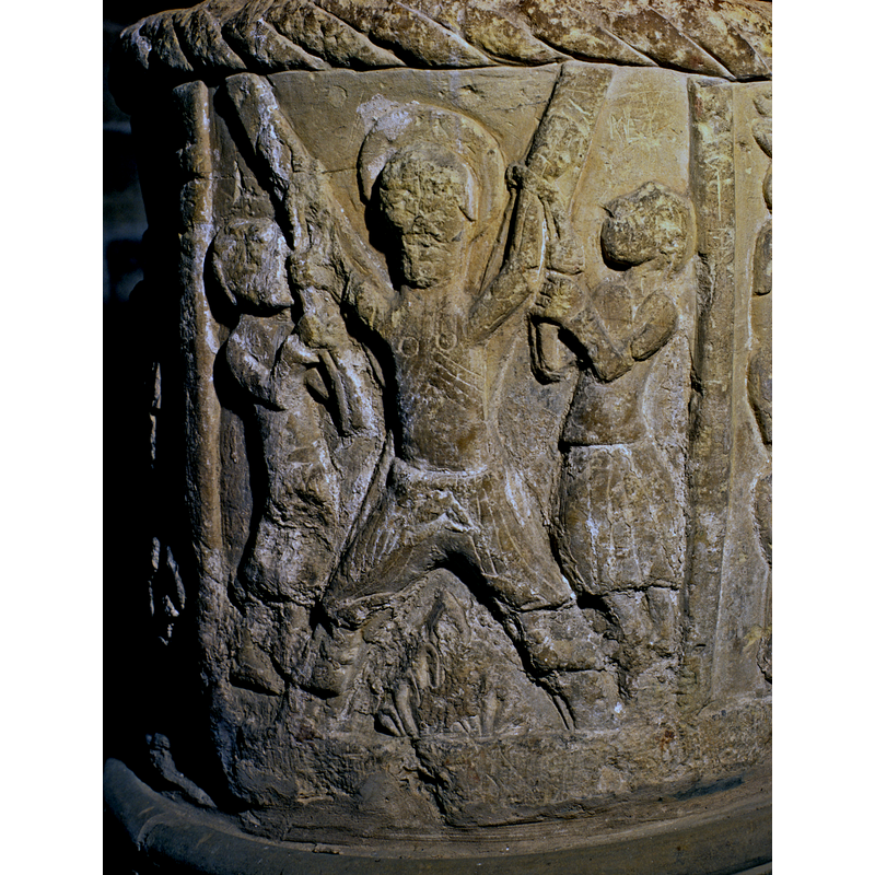 No arch on this scene, but two columns frame the Martyrdom of St. Andrew. He is haloed, full frontal, legs tied to cross and his wrists are being tied by two figures, one to the left and right. He is naked on the chest. A fire appears burning under the cross.