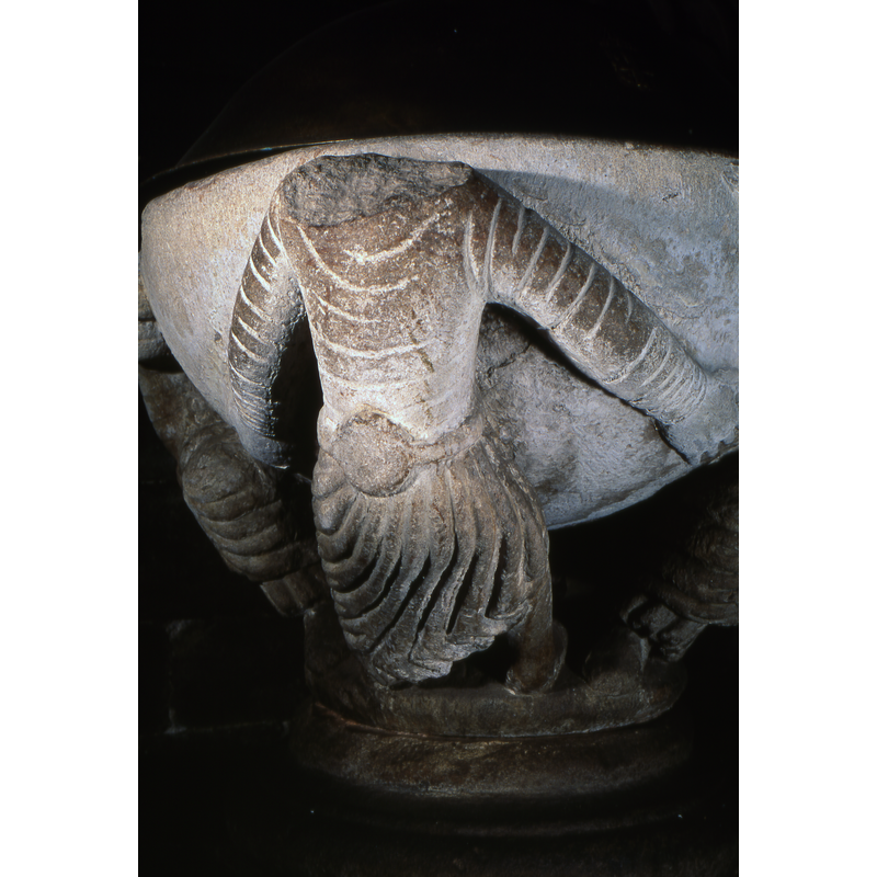 Although identified in Chatel (1966) as caryatids supporting the holy water stoup [sic], the Phaidon guide to France mentions a baptismal font with figures. On-site observation showed a male figure wearing a wrestler or weight-lifter belt.