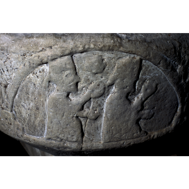 Scene is represented in two arches. The first shows two magi; the second arch depicts the third magus kneeling before an adult Christ figure, enthroned. There is a Romanesque Church carved behind the figure of Christ.