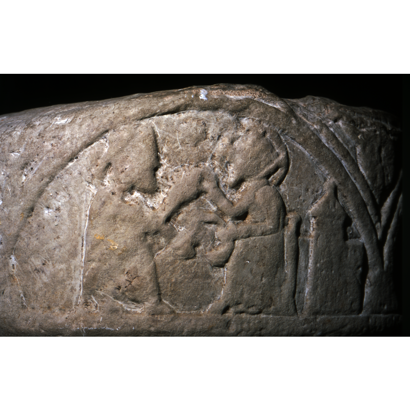 Scene is represented in two arches. The first shows two magi; the second arch depicts the third magus kneeling before an adult Christ figure, enthroned. There is a Romanesque Church carved behind the figure of Christ.