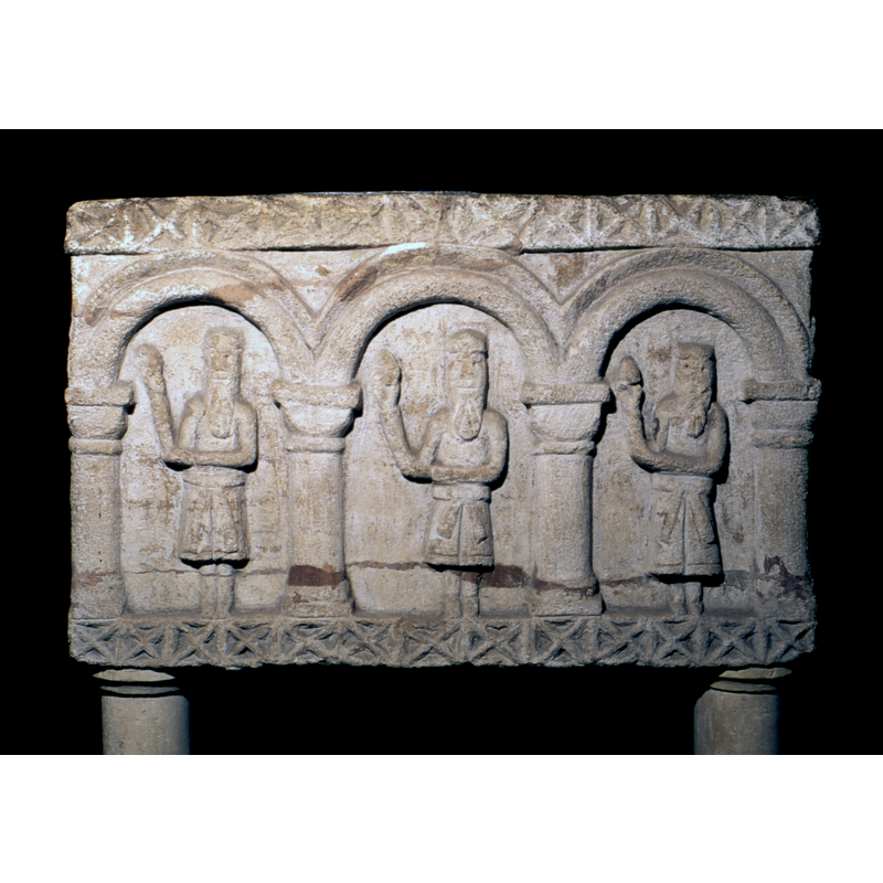 East side: three magi standing holding gifts supporting their right arms at the elbow with their left hands (unusual gesture)