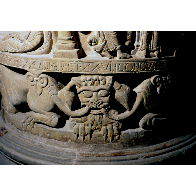 a lion-like head bites the tails of two lions and grasps the rim with its claws; tentatively identified in some authors as a devil, but to thers it is the seventh lion of Daniel's scene