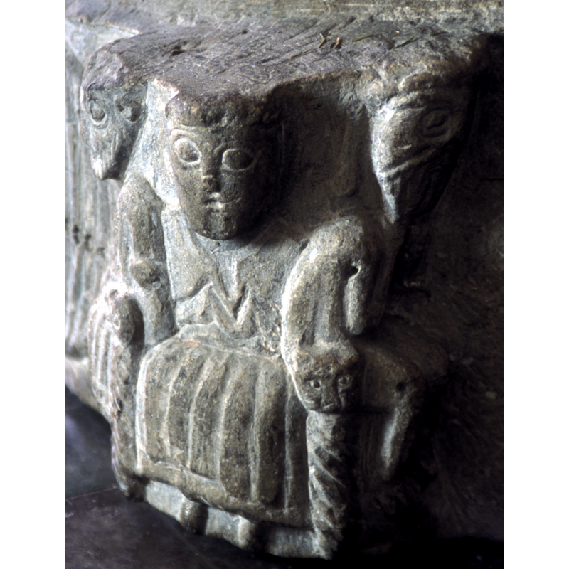 the figure in the centre is clean-shaven and wears rich garments; the arm-rests end in animal heads and the front legs of the throne or chair are decorated with torsade pattern