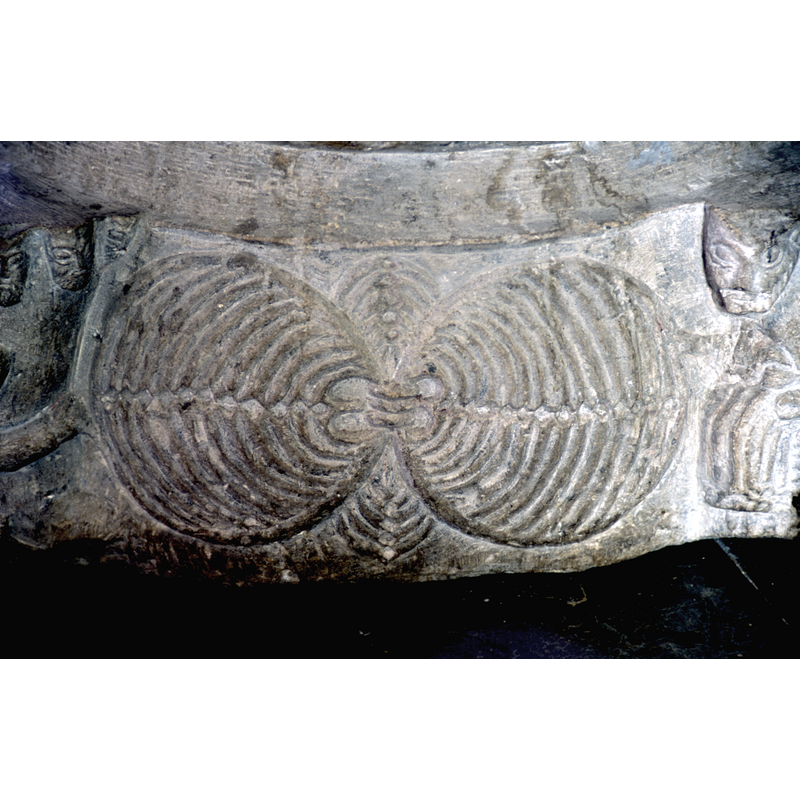 a rare combination carved flat on the side of the base, between two of the protruding motifs (the strong man, on the left, and the three seated figures on the right)