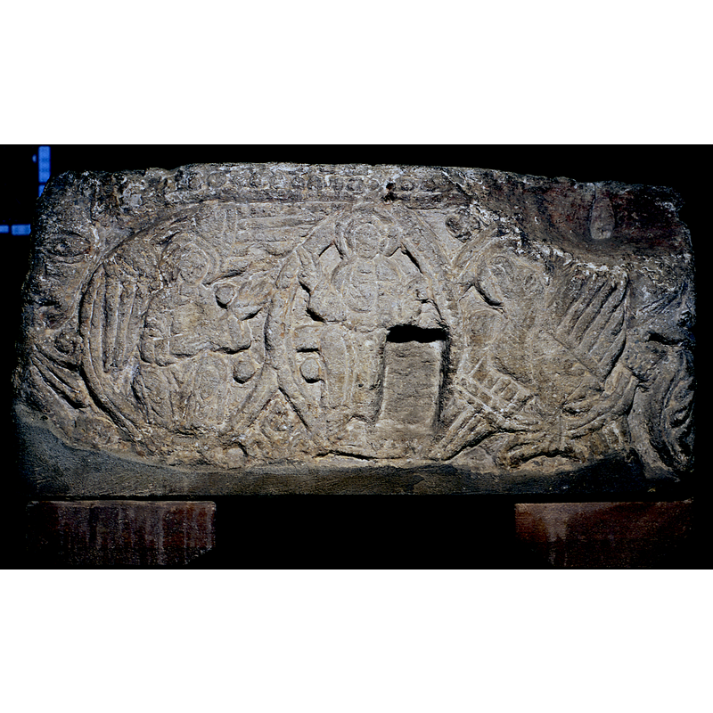 east side of the basin: to the sides of the Maiestas Domini: a haloed angel (the symbol of Matthew?) with extended wings on the left; to the right of the mandorla is a haloed eagle (the symbol of St. John the Evangelist?) with extended wings; a large rectangular block has been cut out of the stone, perhaps to locate a lock of an old cover; deformed heads with vegetation stemming from their mouths at the left and right corners; row of large beads above the scene