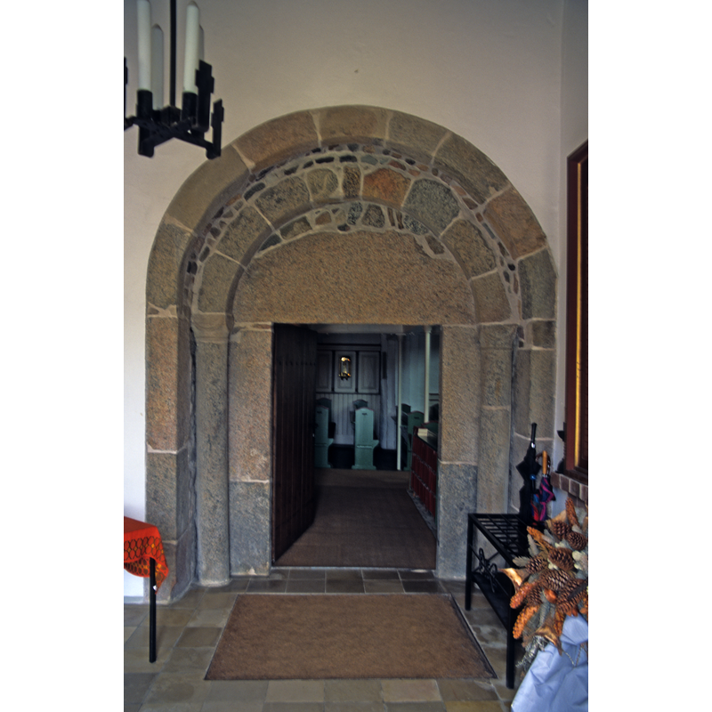 the open door allows for a partial view of the interior of the nave at the west end