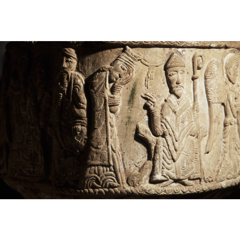 a bishop enthroned with chair ending in animals heads - law throne. The left hand holds staff and the right hand pointed in benediction to the figure on the left. The figure to the left in profile, wearing a tall hat (female?) head is bent and resting on her left hand in sorrow gesture. In between the two figures is the hand of god.