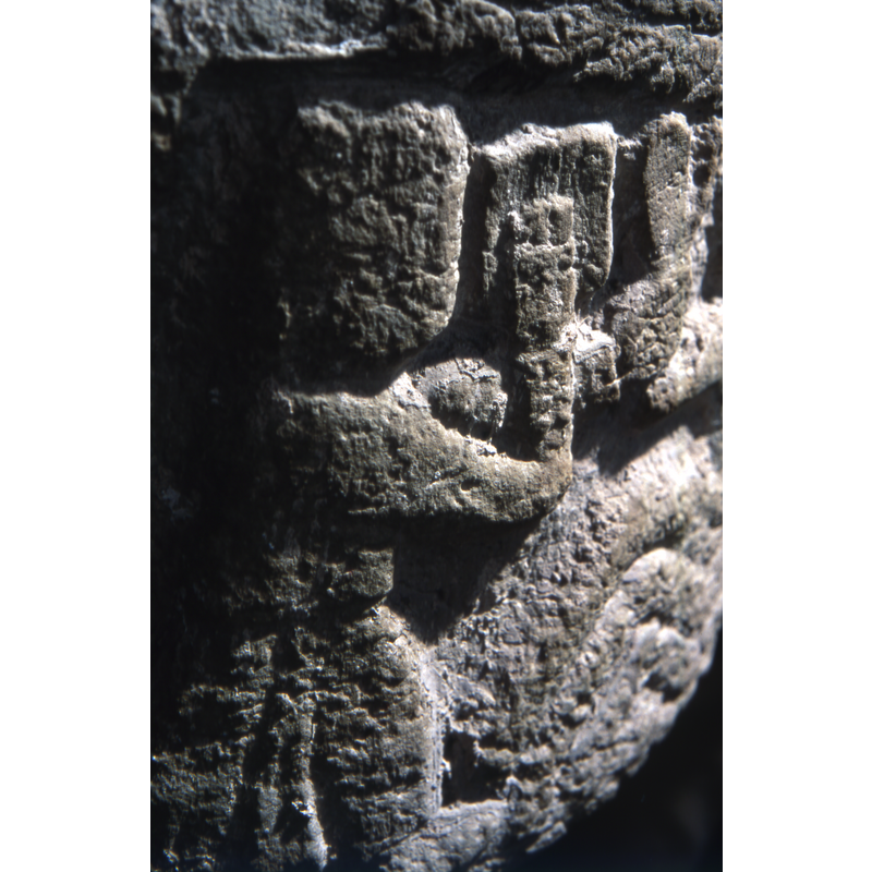 Baptism of Christ? Crudely depicted. To the left a figure in profile, holds a book, open with right hand and the left hand holds the wrist of the person's arm in the water. To the centre and right, three thick wavy lines for water, above it a person, full frontal, up to the waist, right arm extended to the figure on the left. The left hand of the person in the water holds a staff to his chest - but no cross on it.l