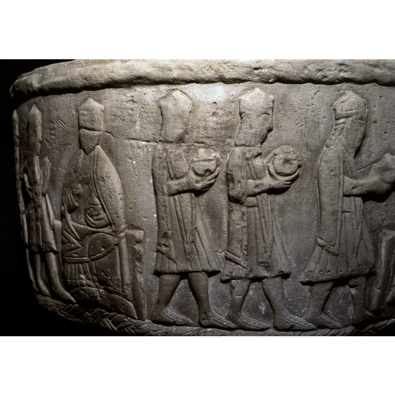  the Magi [only two visible in this image] walk toward a crowned enthroned figure on the right; his left hand holds a covered recptacle [a chalice?]; his right hand appears to be raised [the carving is worn here]; is the scene deliberately ambiguous so that the seated figure appears to be Christ-like? Trompe l'oeil? -- in the left of the image the three Magi walk carrying gifts, part of the Adoration scene fully visible in the next image