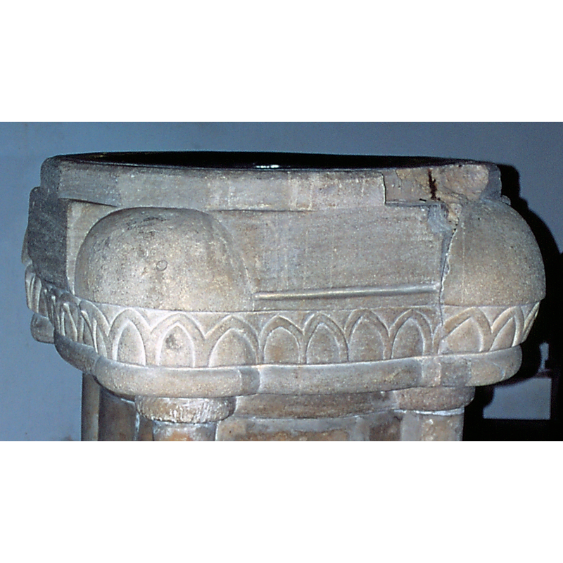 the pattern of rather  irregular pointed arch-heads ends at the left end, where the pattern of intersecting round arches start -- the samage visible on the upper rim, right side, still shows the rust colour of the metal staple that served as anchoring for an old font