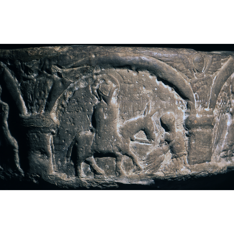 Triumphal Entry into Jerusalem on Palm Sunday; Jesus, haloed, rides on an ass with long ears; to the right is a figure kneels and lays out a cape (?) for the animal to walk on
