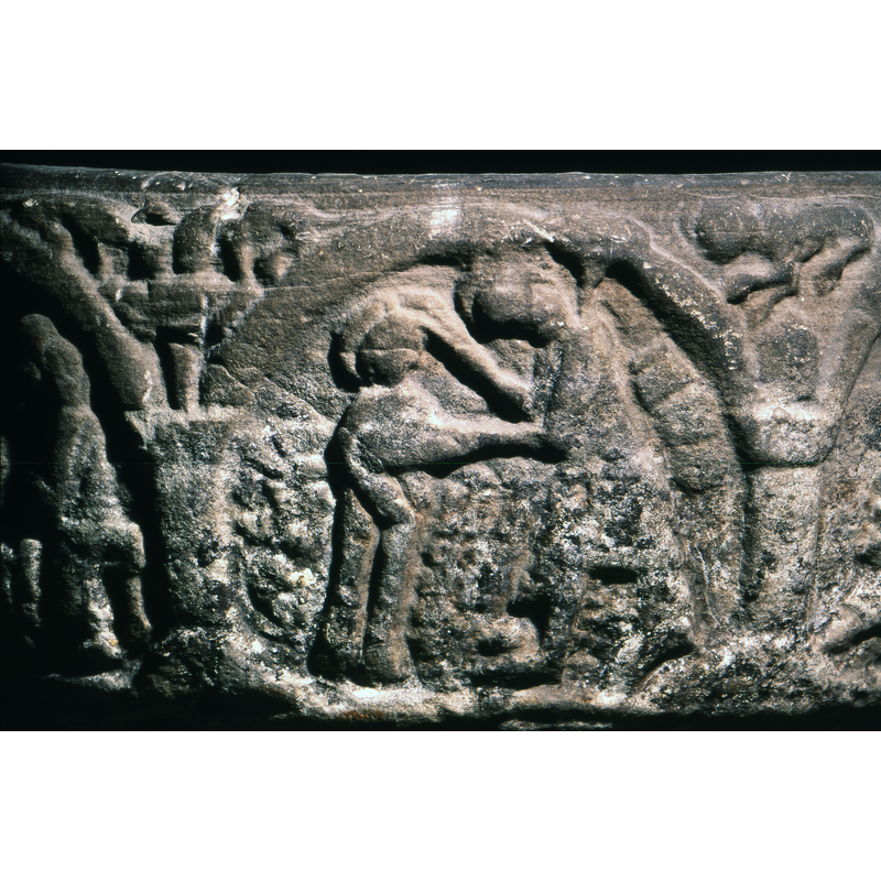 The Baptism of Christ. Christ stands in water to the waist (shown as round carved dots) to the left. To the right stands St.John the Baptist with his left arm across the chest of Christ and his right resting on top of his head. Both figures are haloed.
