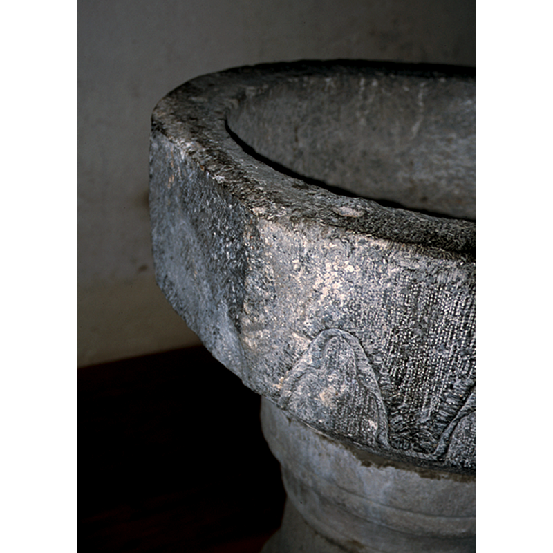 the plain side seen here on the left could have been either an unfinished side intended for the font to be agaisnt a wall or furnishing, or, more likely, that this side of the font was re-cut to fit the font into a new and tight space [NB: this type of re-cutting has unfortunately happened often to fonts all over]