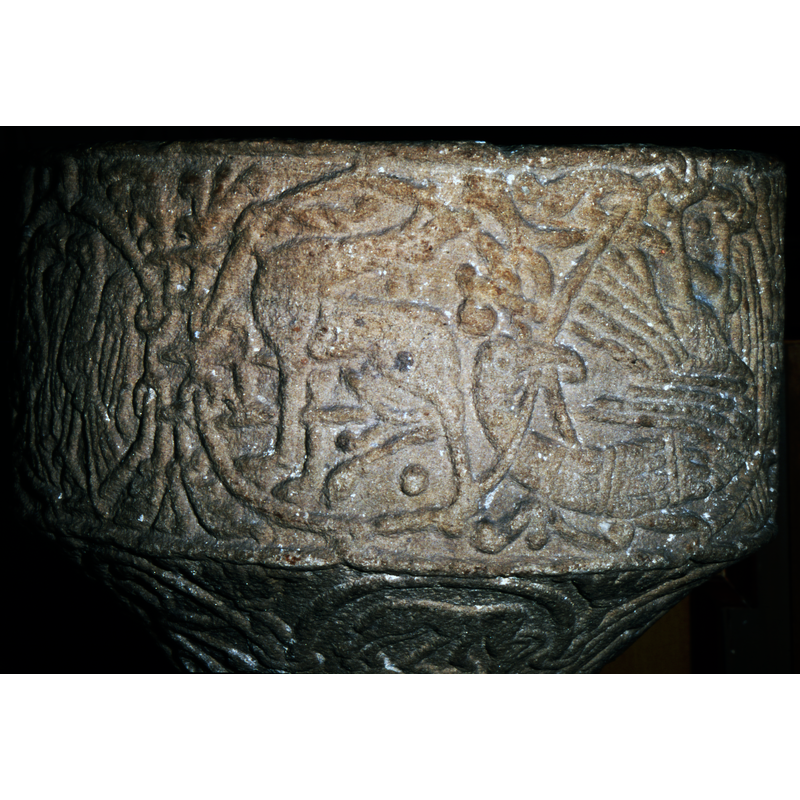 Moving from Left to Right, four legged animal facing left, entwined with vegetation