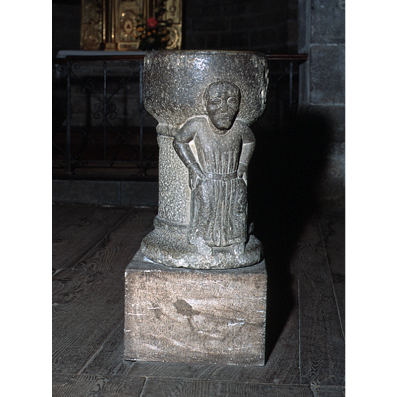 Two male figures, on opposite sides of the stoup, standing with hands on their haunches