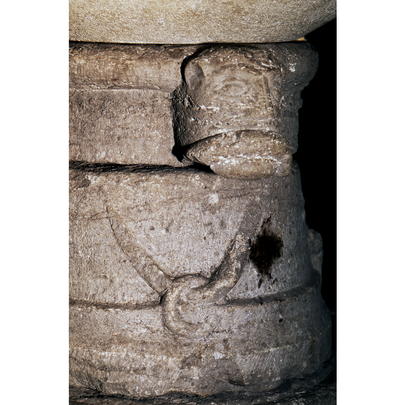 a rope (?) zig-zags through round links of chain that are carved on the lower sides